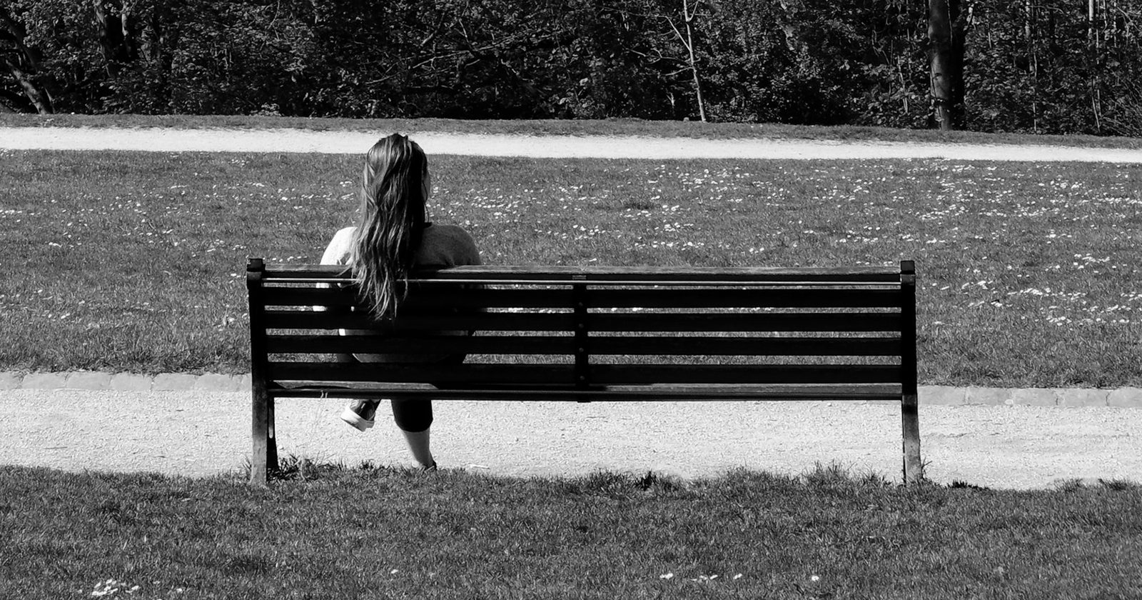 A woman sitting on a bench in a park.