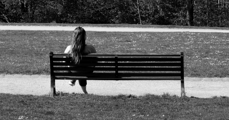 A woman sitting on a bench in a park.